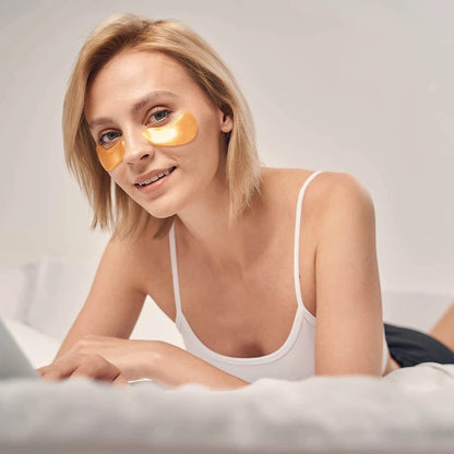 Woman wearing Satavi Naturals 24K gold under eye masks while relaxing at home.